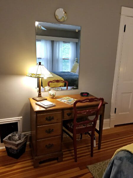 Small wood desk with a mirror and a table lamp with stained glass shade