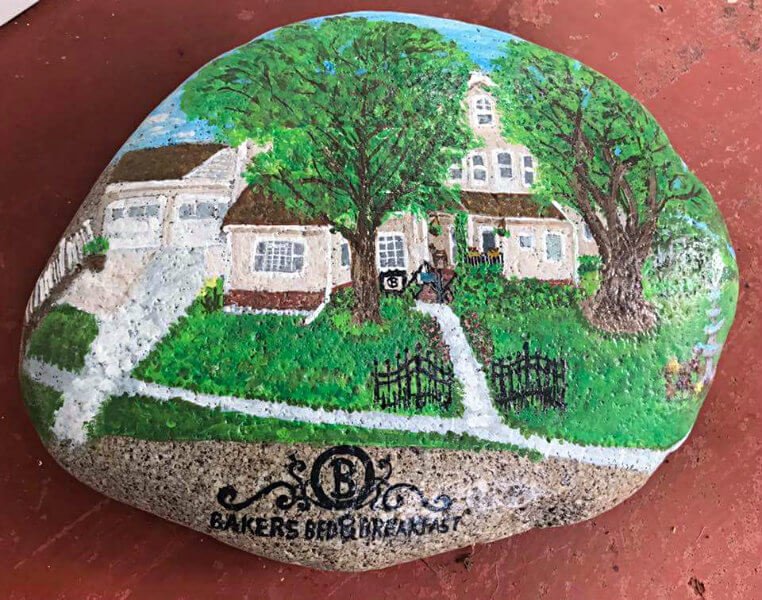 Up close view of a rock with a colorful painting of Bakers Bed and Breakfast