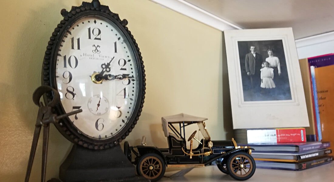 Old fashioned metal clock, old-fashioned model kit car, stack of book and old black and white photo